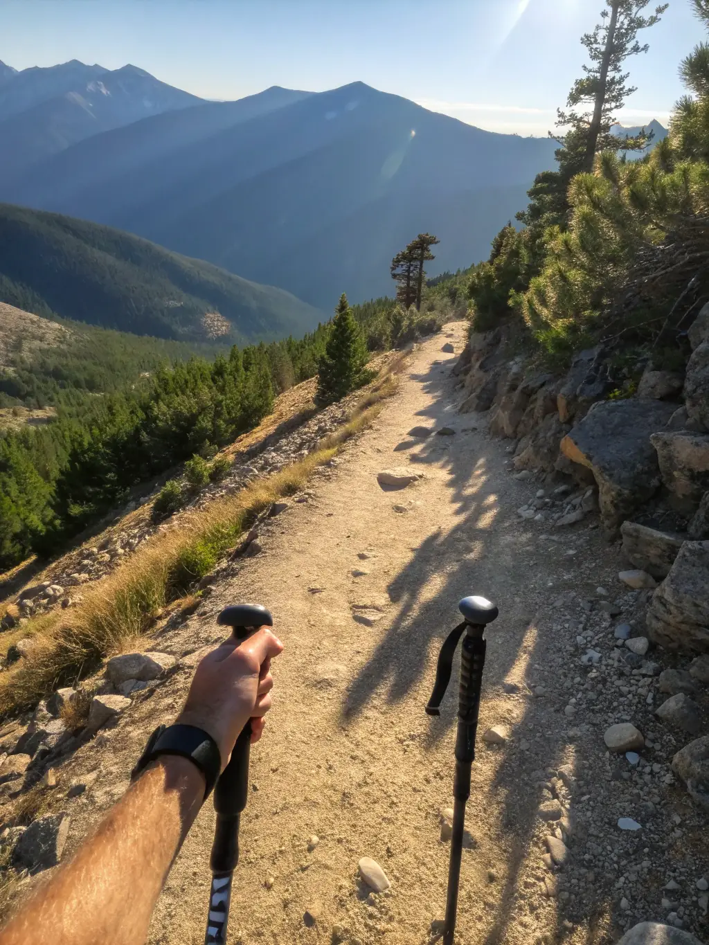 A scenic view of a hiker stopping to pack out trash on a mountain trail, emphasizing the importance of leaving no trace.